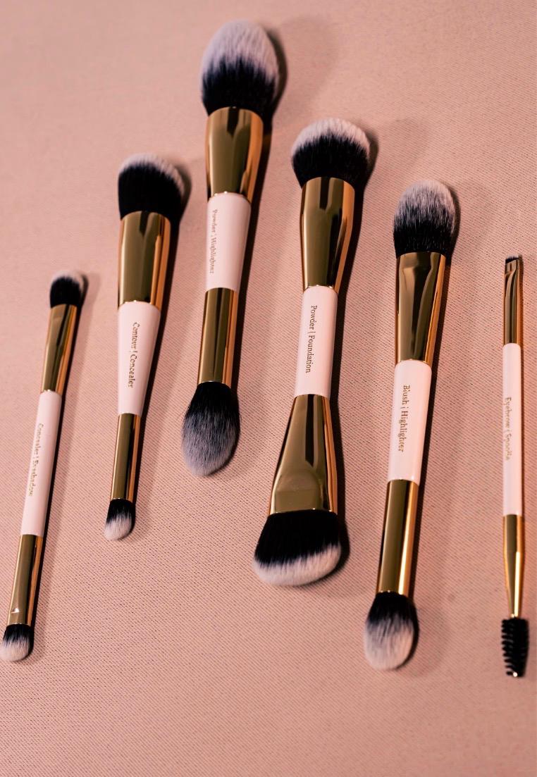Les 6 pinceaux 2-en-1 PAYSIA dressés sur fond nude, gravures Concealer, Contour, Powder, Foundation, Blush, Eyebrow et Spoolie